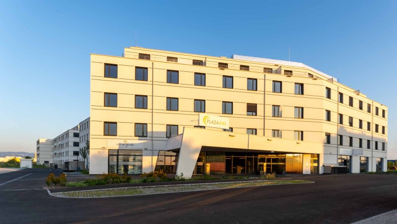 A modern, multi-storey building with the inscription 'Plaza INN' at sunset.