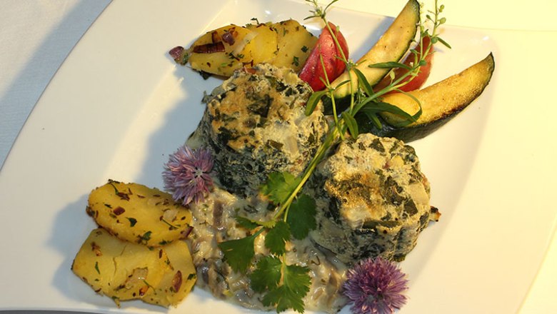 A plate of spinach dumplings, potatoes and vegetables arranged decoratively.