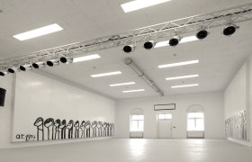 Interior view of a white room with wall paintings and lighting.