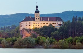 Persenbeug Castle on a hill with a river in the foreground.