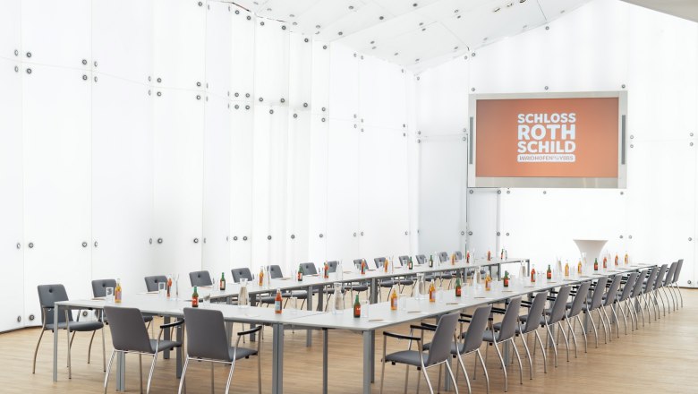 Modern conference room in Rothschild Castle with long tables, chairs and drinks.