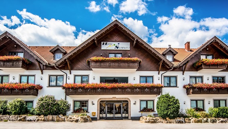A traditional hotel with wooden balconies and flower boxes against a blue sky.