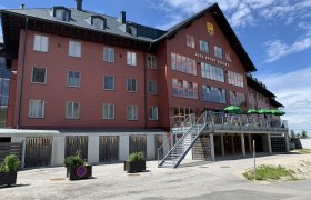 JUFA Sport Resort Hochkar with red facade and terrace with green sunshades.