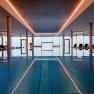 Interior view of an infinity pool with sun loungers and large windows.