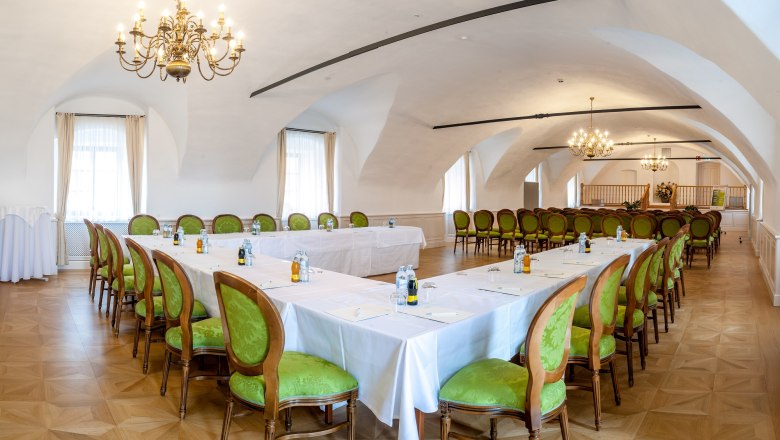 Elegant conference room in Thalheim Castle with green chairs and chandeliers.