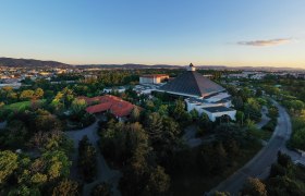 Aerial view of the Eventhotel Pyramide with surrounding landscape at sunset.