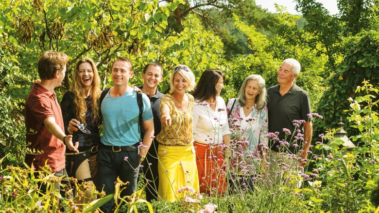 A group of people stand smiling in a blooming garden.