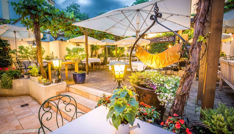 Guest garden in the evening with lighting and plenty of seating, plants and umbrellas.