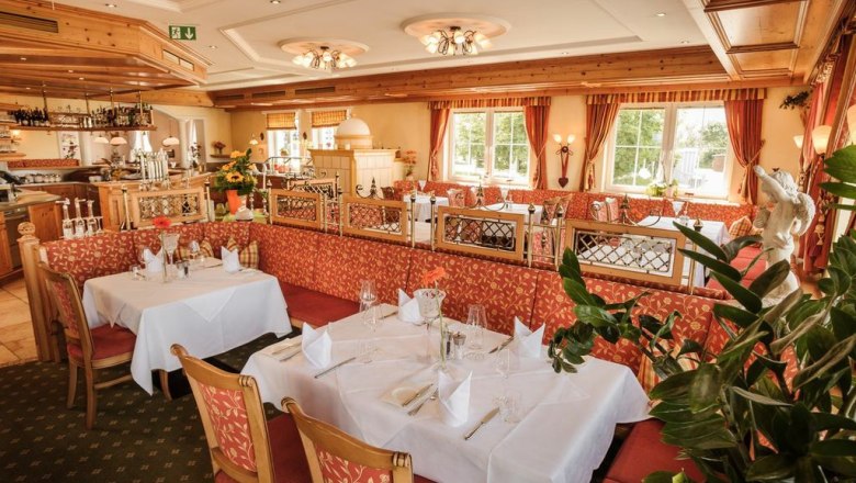 Elegant restaurant with laid tables and red upholstered furniture.