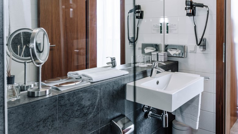 Modern hotel bathroom with washbasin, mirror and towels.