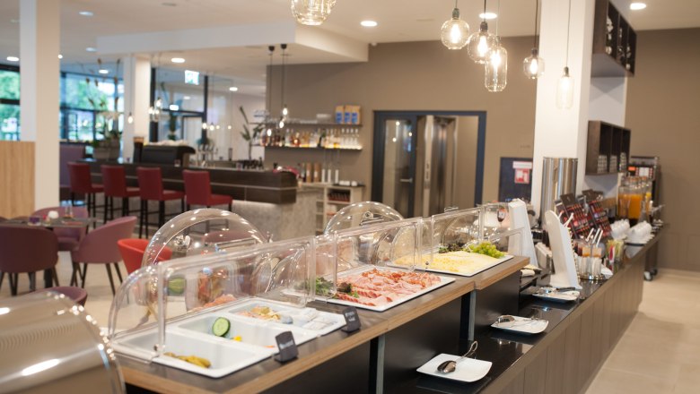 Breakfast room with several tables and breakfast buffet