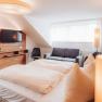 Modern hotel room with double bed, sofa, TV and stylish lighting.