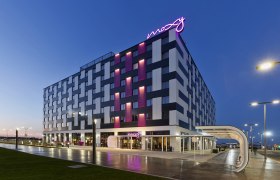 Exterior view of the Moxy Vienna Airport Hotel at dusk with illuminated lettering.