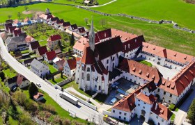 Aerial view of Gaming Charterhouse with surrounding buildings and green fields.