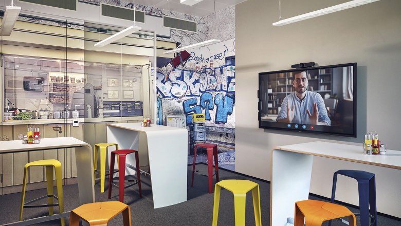 Modern conference room with graffiti wall, colorful stools and video conference screen.