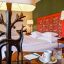 A stylishly furnished hotel room with a bed, decorative lamps and a table with a cup and glass.