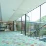 Modern, glazed passageway with colorful carpet and wall art.