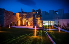 Illuminated ruins and modern architecture at night.