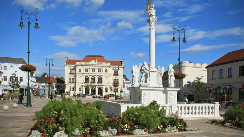 Main square in Tulln with baroque column and historic buildings.