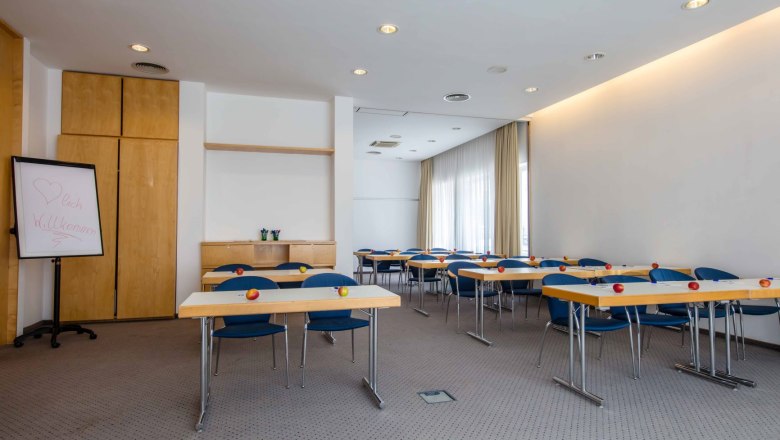 A seminar room with tables, chairs and apples on the tables.