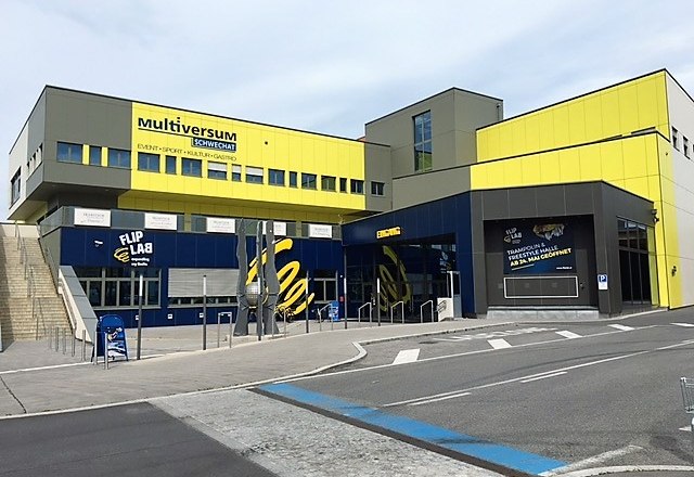 Exterior view of the Multiversum Schwechat, a modern building with yellow and blue facades.