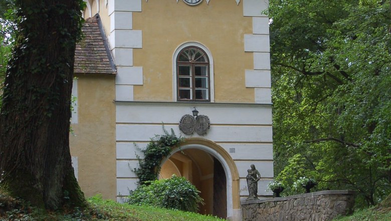 Historic building with tower and clock in a wooded area.
