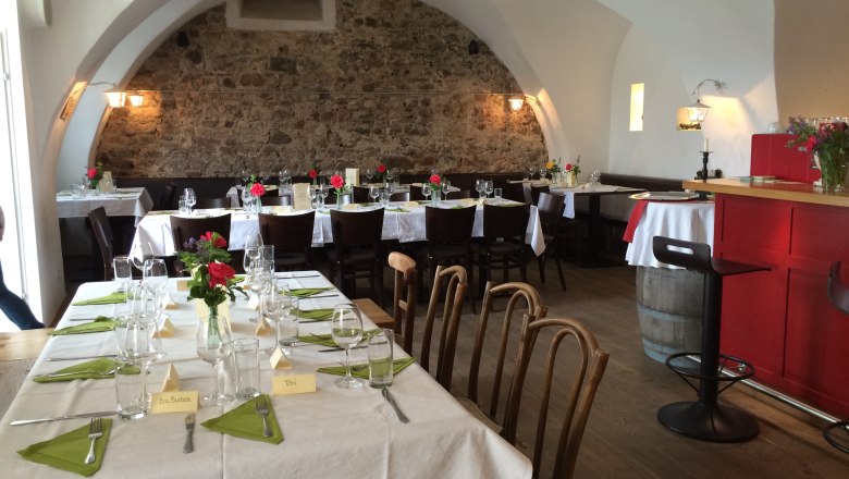 Cozy dining room with covered tables, stone wall and vaulted ceiling.